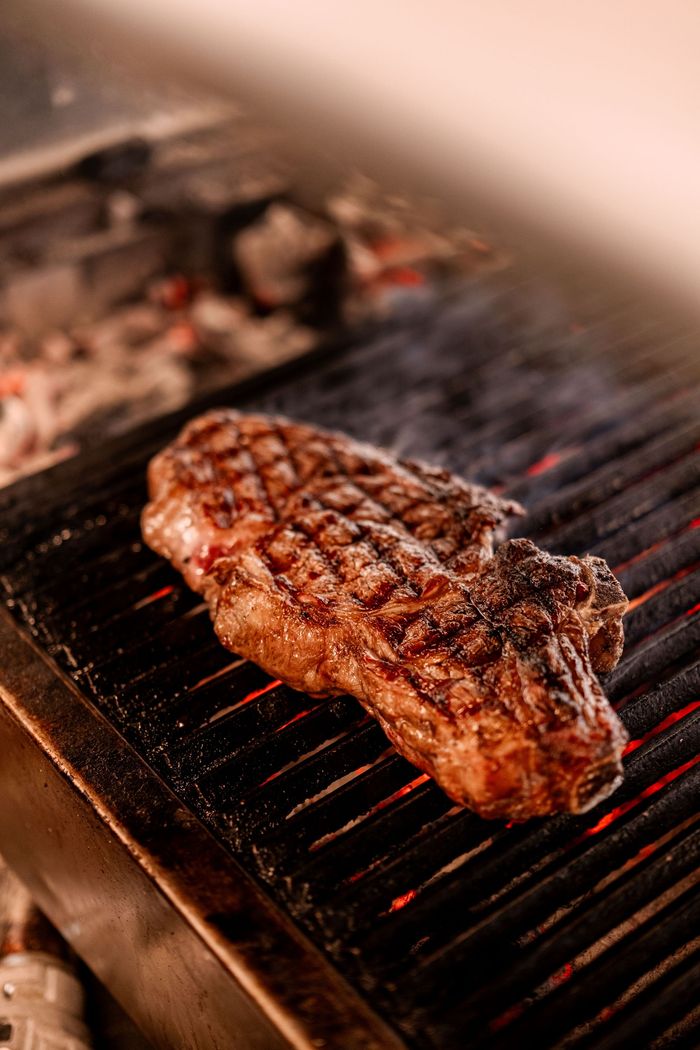 Un steak grillé qui saisit sur un barbecue bien chaud, avec des marques de grillade bien prononcées et une chaleur fumante.