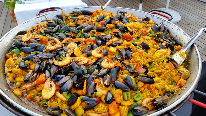 Plat de paella colorée aux fruits de mer, avec des moules, des crevettes et du riz, dans une grande poêle