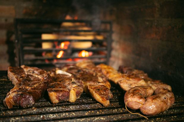 Des steaks grillent à feu vif dans un barbecue, avec des flammes rougeoyantes en arrière-plan