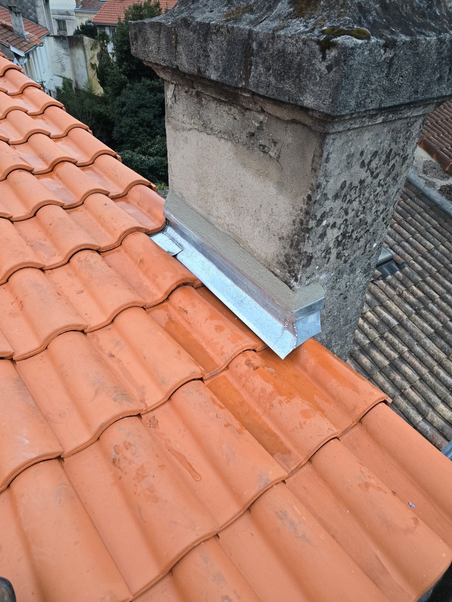 Travaux de zinguerie pour une cheminée sur une toiture en tuiles