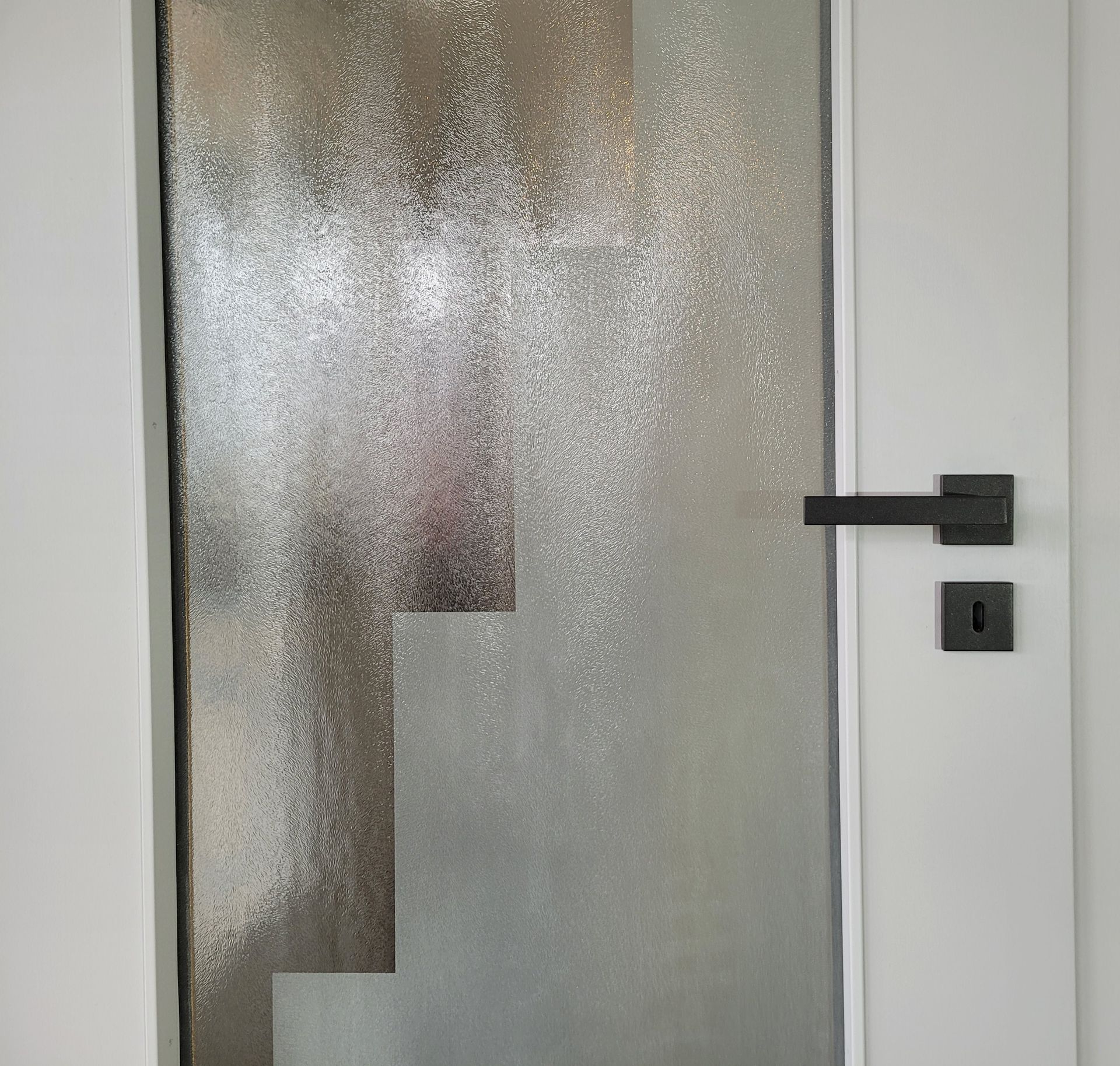 weiße Tür mit schwarzem Handgriff und Glaswand