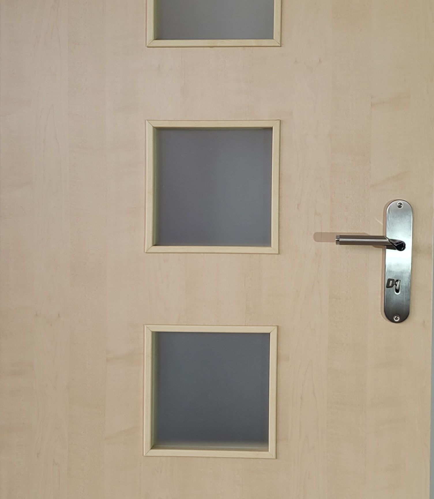 Eine Holztür mit drei quadratischen Fenstern und einem Türgriff.