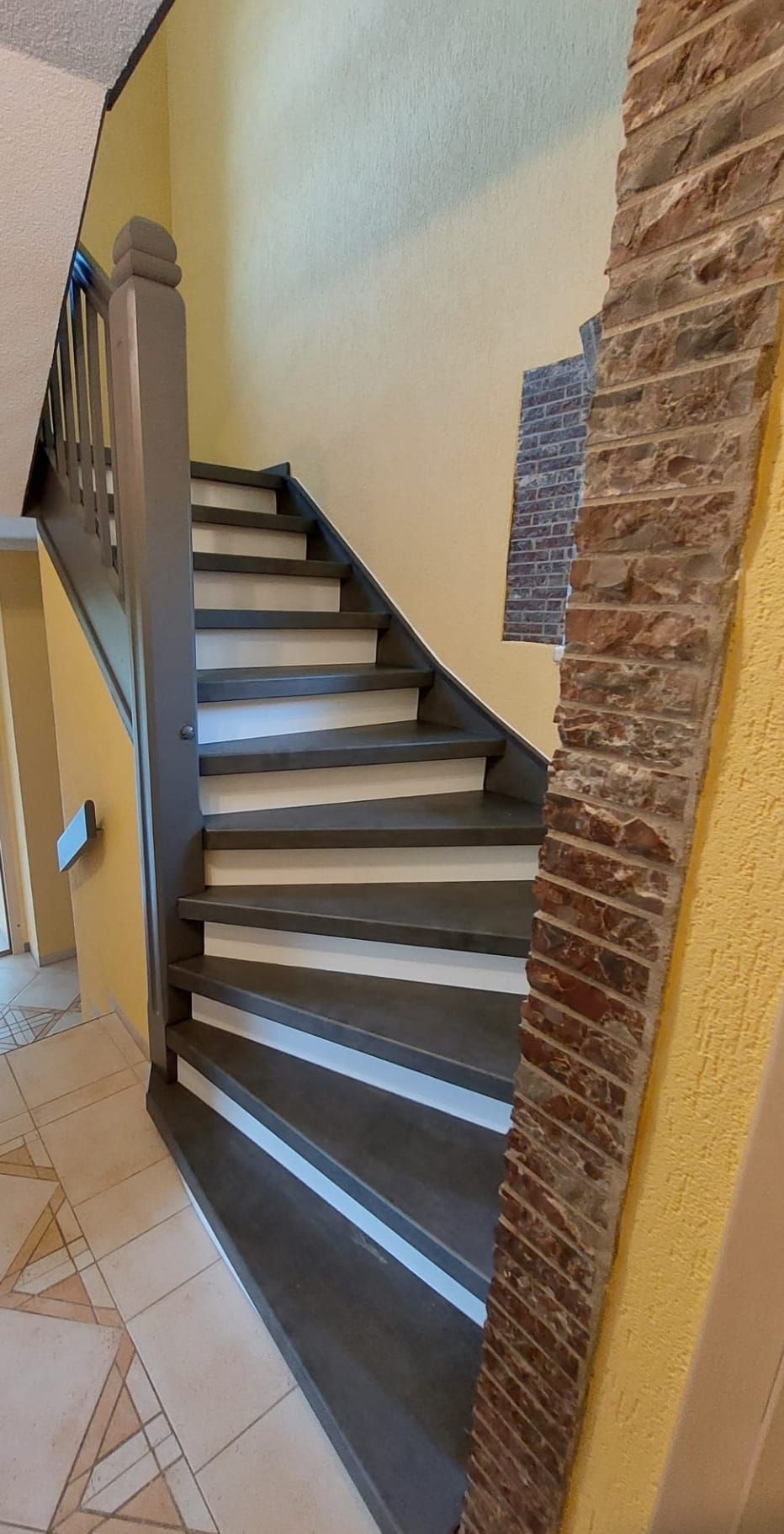 Eine Treppe mit einem Holzgeländer und einer Ziegelwand in einem Haus.