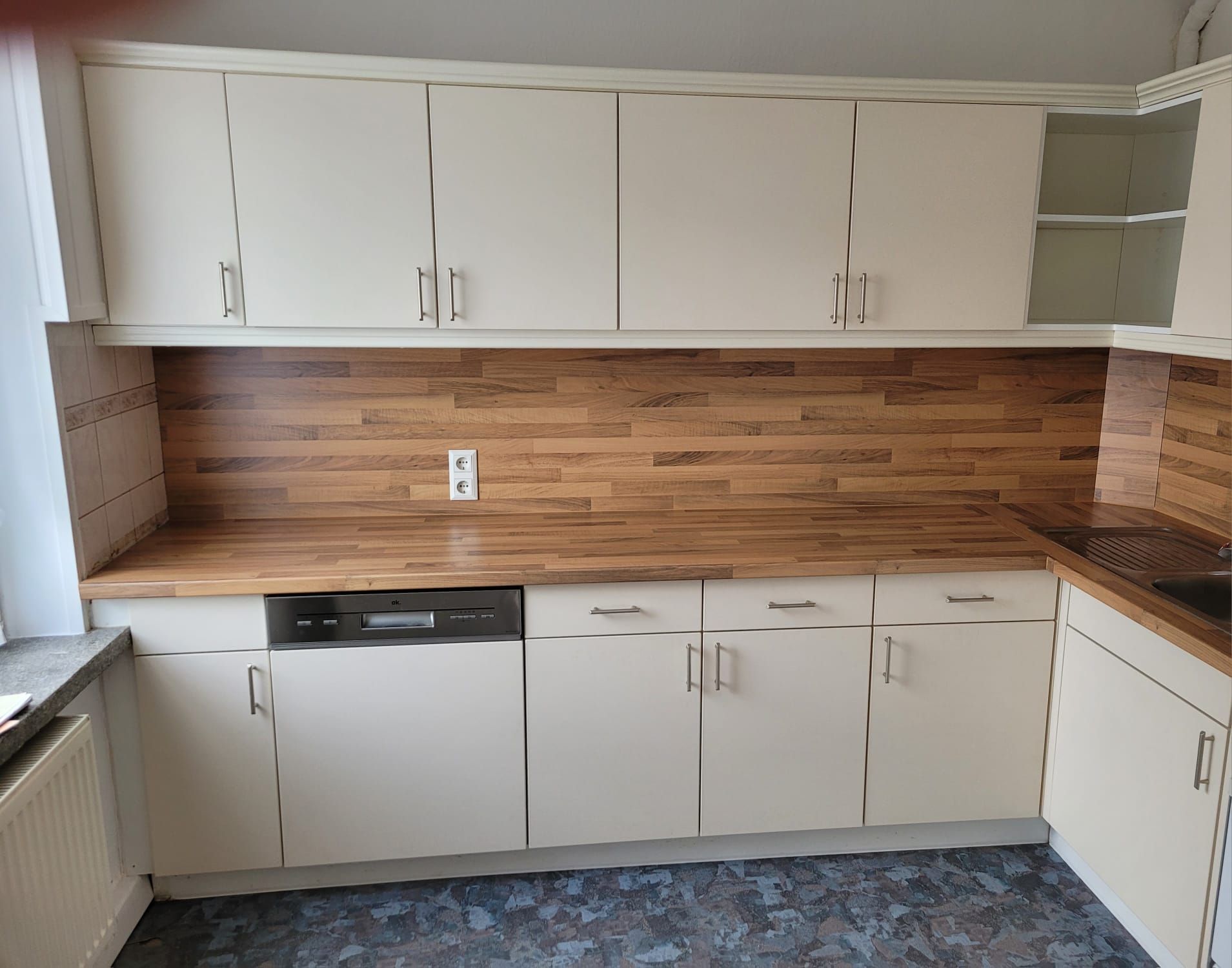 Eine Küche mit weißen Schränken und einer Arbeitsplatte aus Holz.