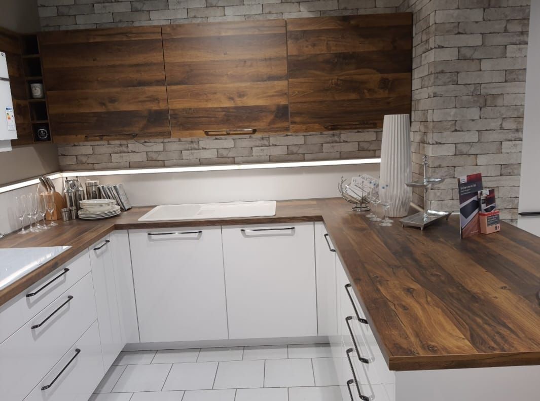 Eine Küche mit weißen Schränken und einer Arbeitsplatte aus Holz.