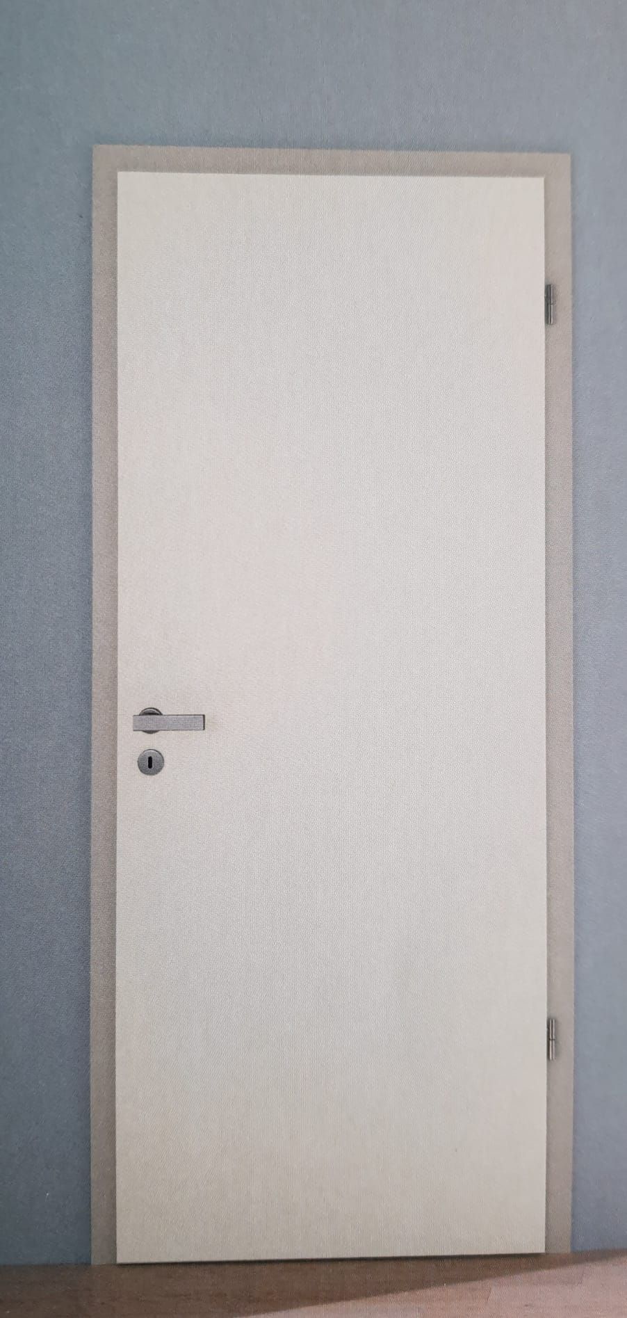 Vor einer blauen Wand steht eine weiße Tür mit einem Griff.