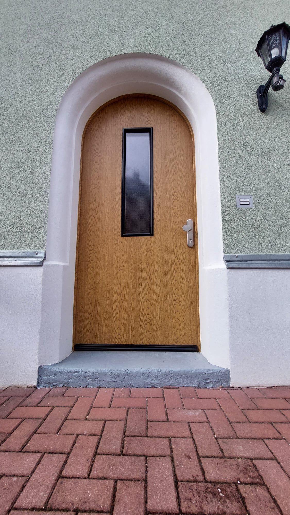 Eine Holztür mit einem gemauerten Gehweg davor