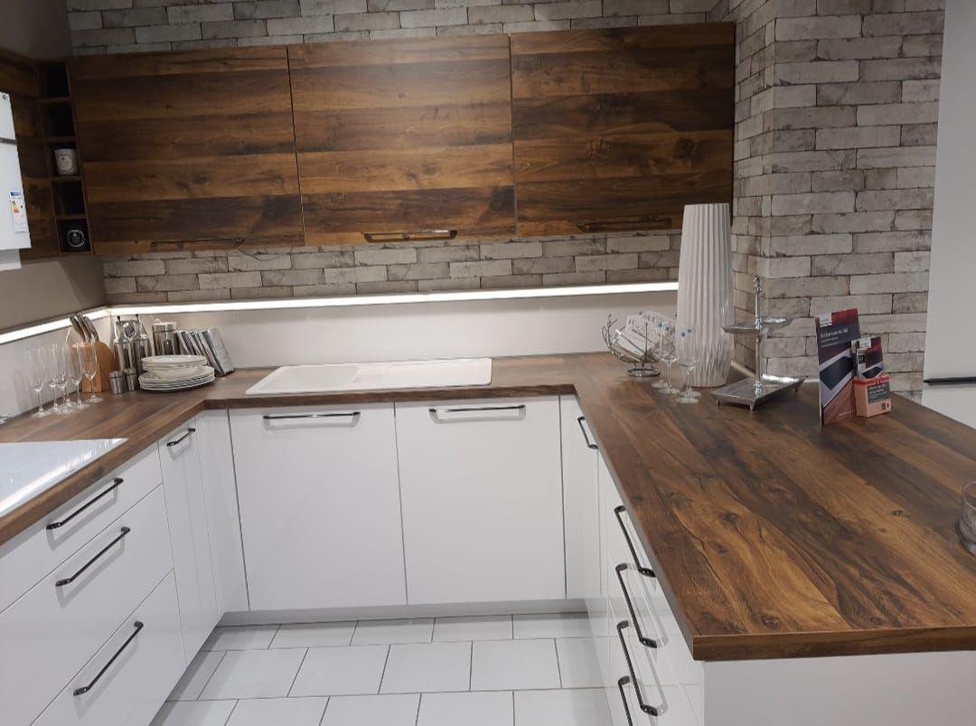 Eine Küche mit weißen Schränken und einer Holzarbeitsplatte