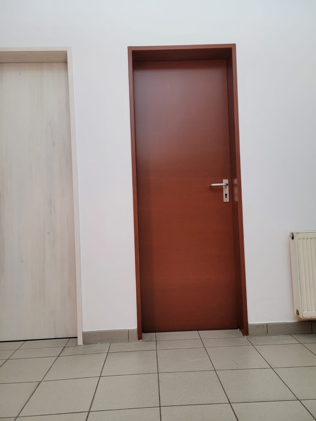 Ein Raum mit zwei Türen und einem Heizkörper an der Wand