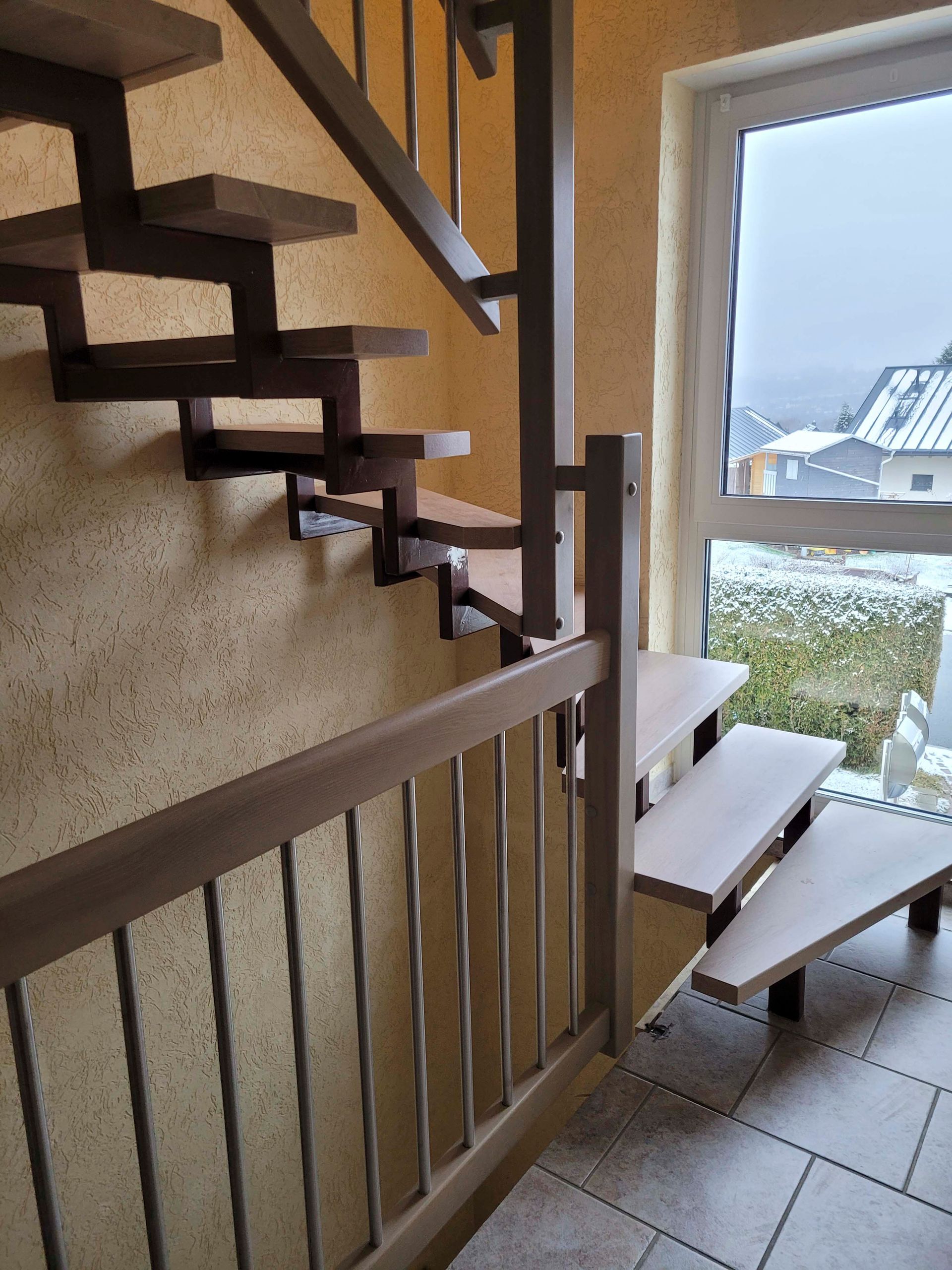 Eine Holztreppe mit einem Metallgeländer und einem Fenster