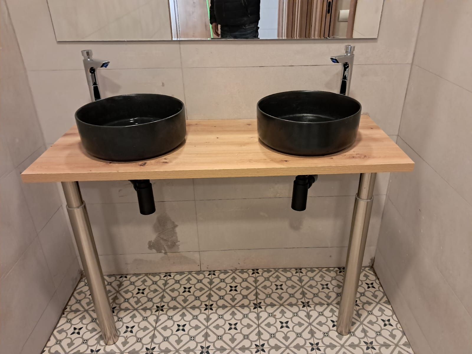 Un baño con dos lavabos negros y un espejo.