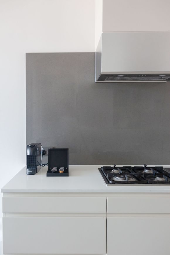 Modern kitchen counter with coffee machine, utensils, gas stovetop, and stainless range hood
