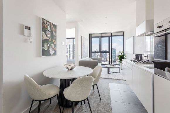 Bright modern kitchen and dining area with white furniture, black accents, and balcony view