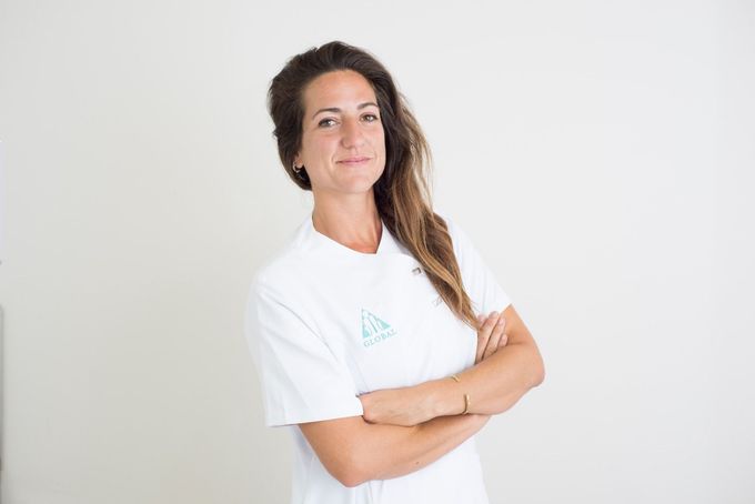 Una mujer con una camisa blanca está de pie con los brazos cruzados.