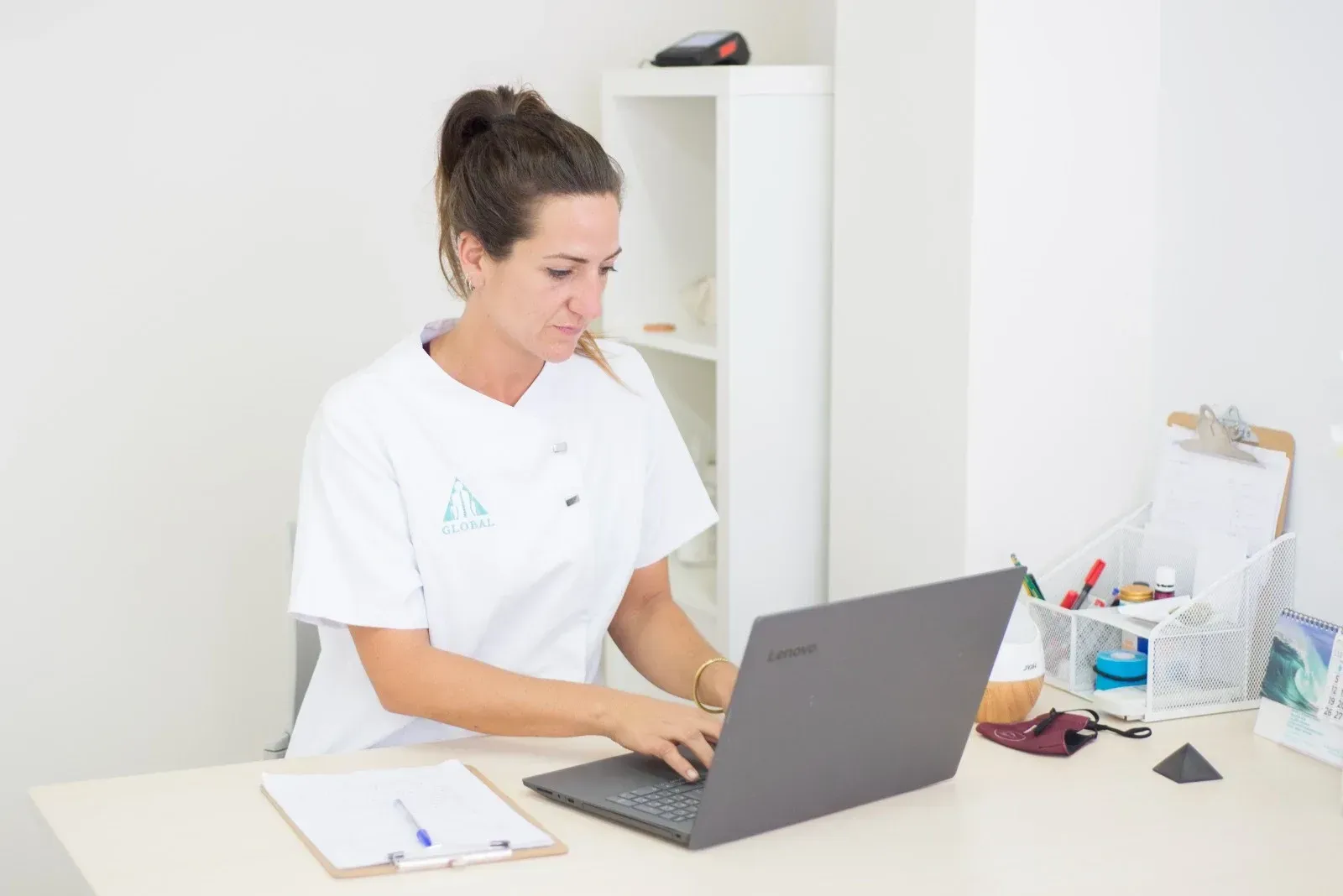 Una mujer está sentada en un escritorio utilizando una computadora portátil.