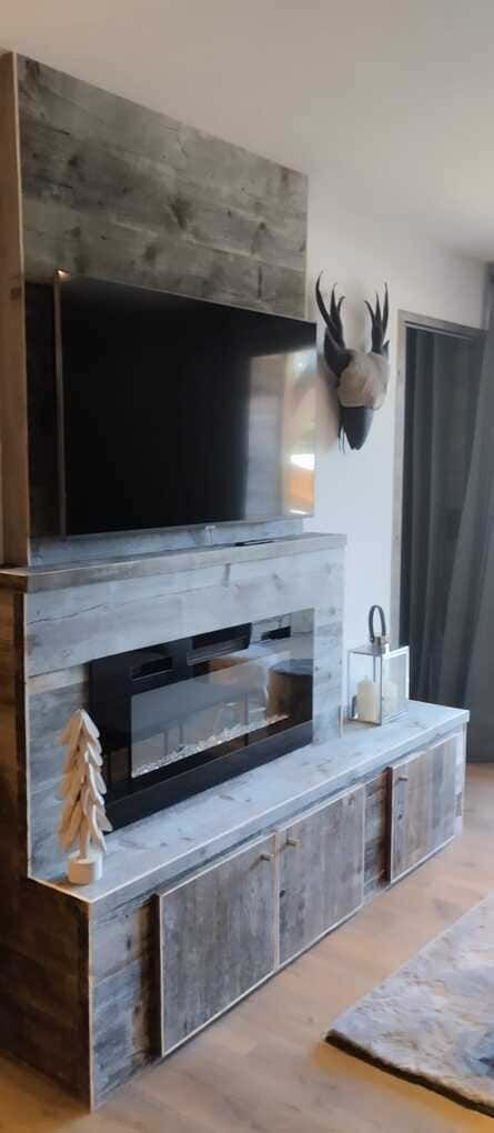 Salón moderno con chimenea de piedra, televisor montado en la pared y mueble multimedia de madera