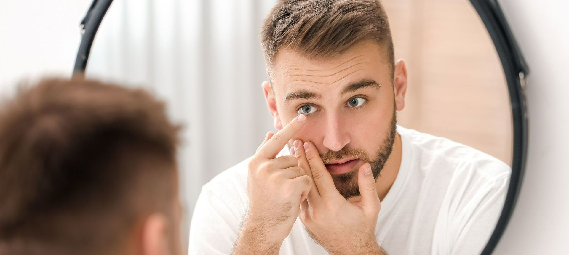 Un homme met ses lentilles de contact