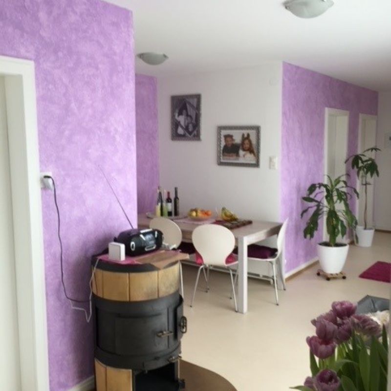 Ein Wohnzimmer mit lila Wänden und einem Tisch und Stühlen. Foto von Saladin Maler