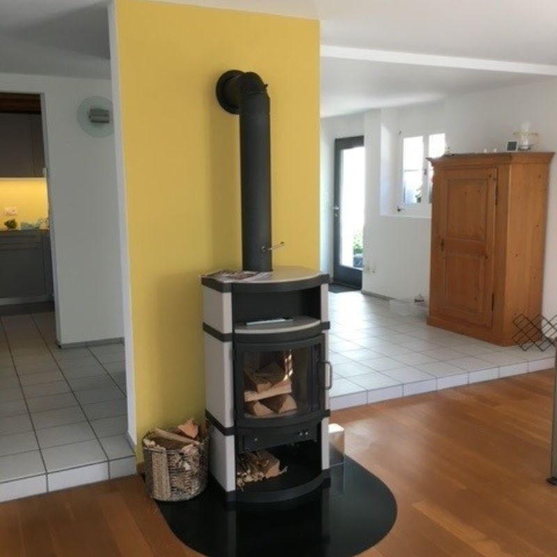 Ein Kamin in einem Wohnzimmer neben einer gelben Wand. Foto von Saladin Maler