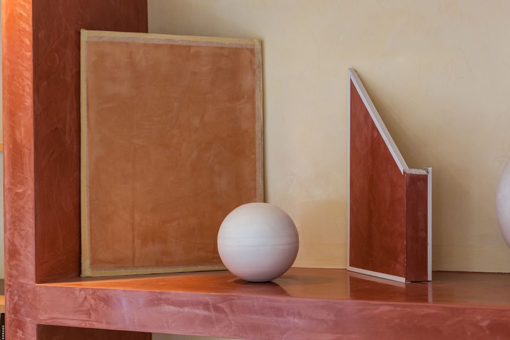 Auf einem Holzregal liegt neben einem Bild ein weißer Ball.