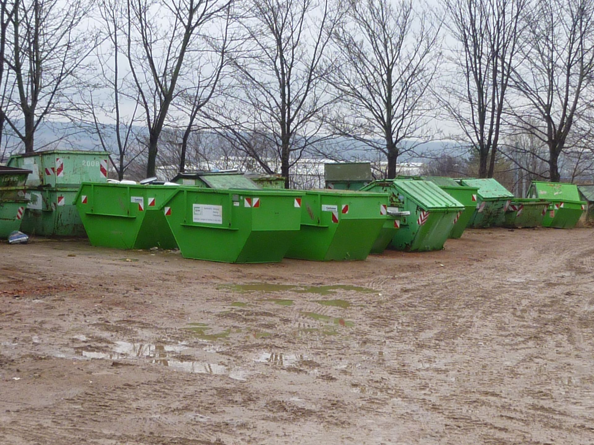 Zwei grüne Recyclingbehälter, einer groß und einer klein, mit dem Recyclingsymbol an der Seite.