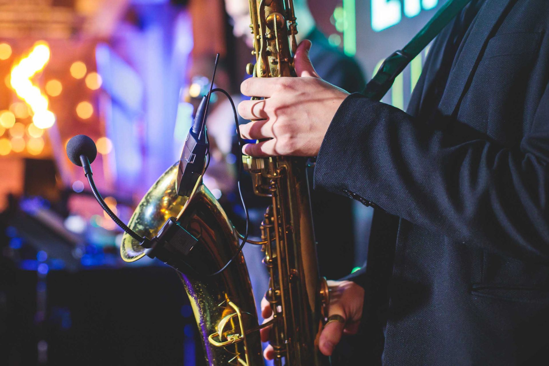 Un hombre con traje toca un saxofón con un micrófono conectado.