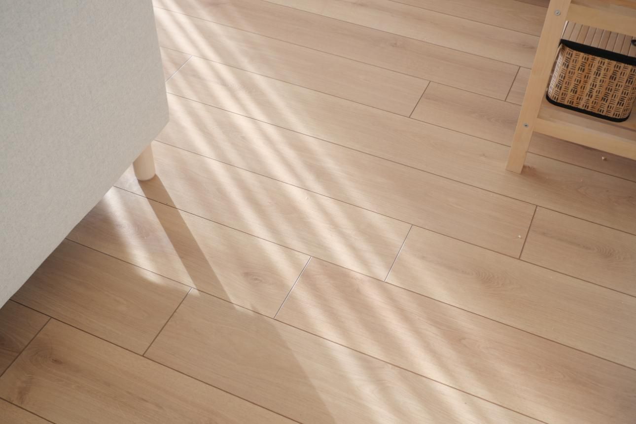 Suelo de madera con franjas de luz solar. Se ve un estante con una cesta.