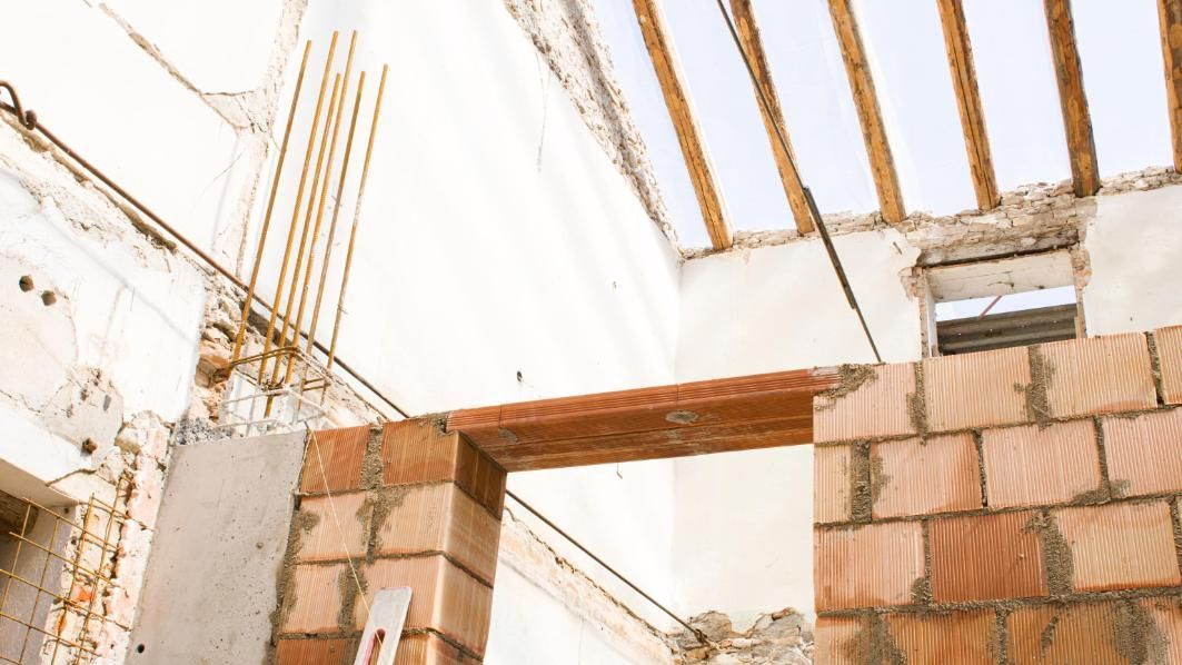 Vista interior de la construcción del edificio con ladrillo y vigas a la vista.