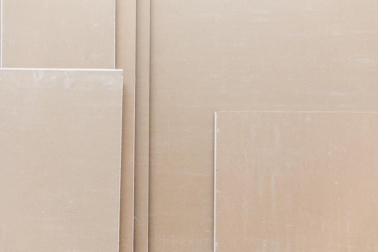 Láminas de yeso beige apiladas y dispuestas, composición vertical.
