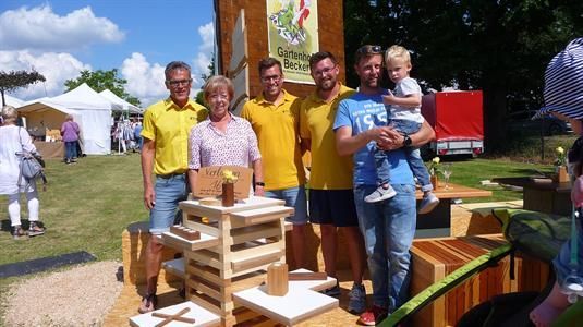 Eine Gruppe von Menschen posiert vor einer Holzkonstruktion für ein Foto.