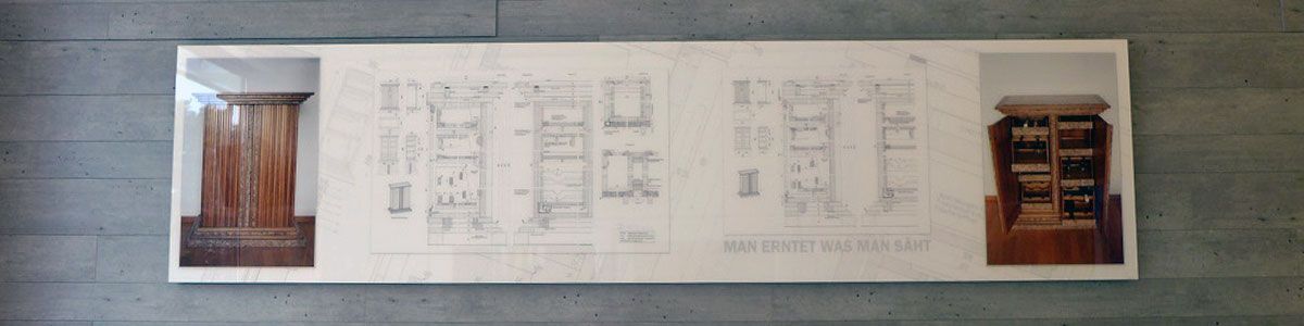 An einer Wand hängt eine Zeichnung eines Holzschranks