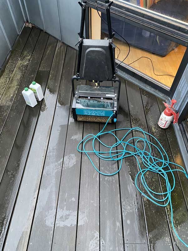 Eine Maschine steht neben einer Sprühflasche auf einem Holzdeck.