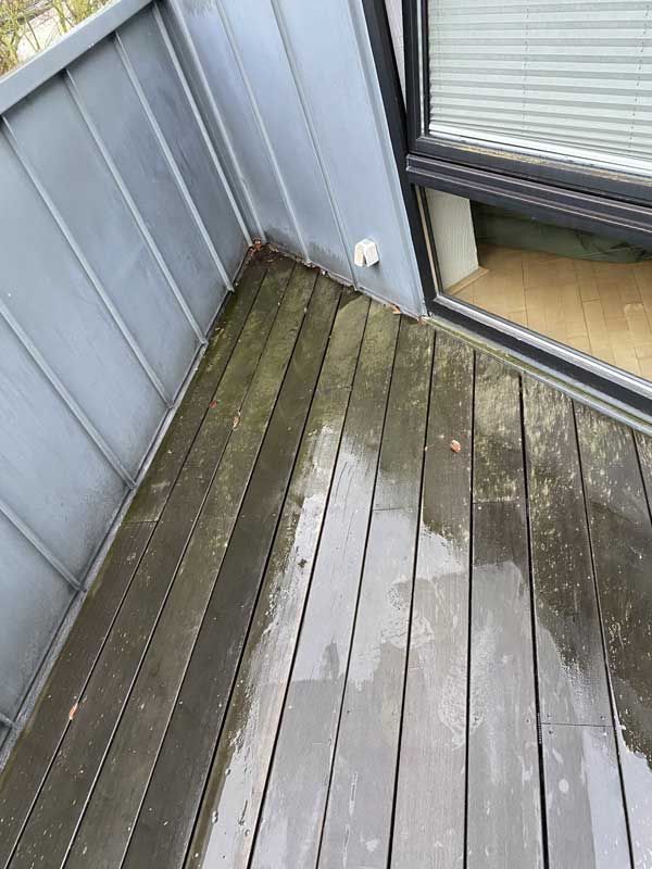 Ein Balkon mit Holzterrasse und Fenster.