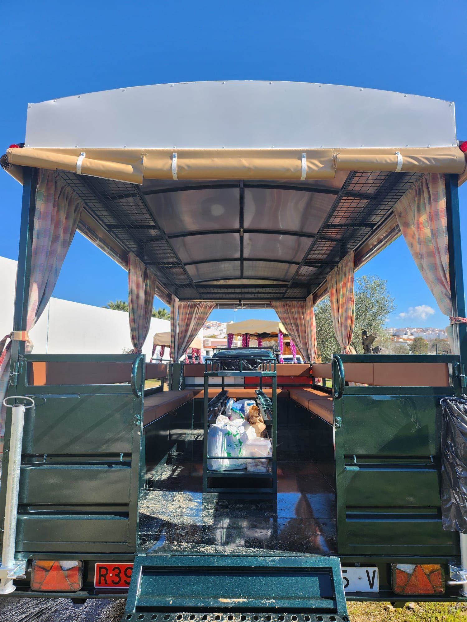 Camioneta verde con toldo cubierto, cortinas y parte trasera abierta.