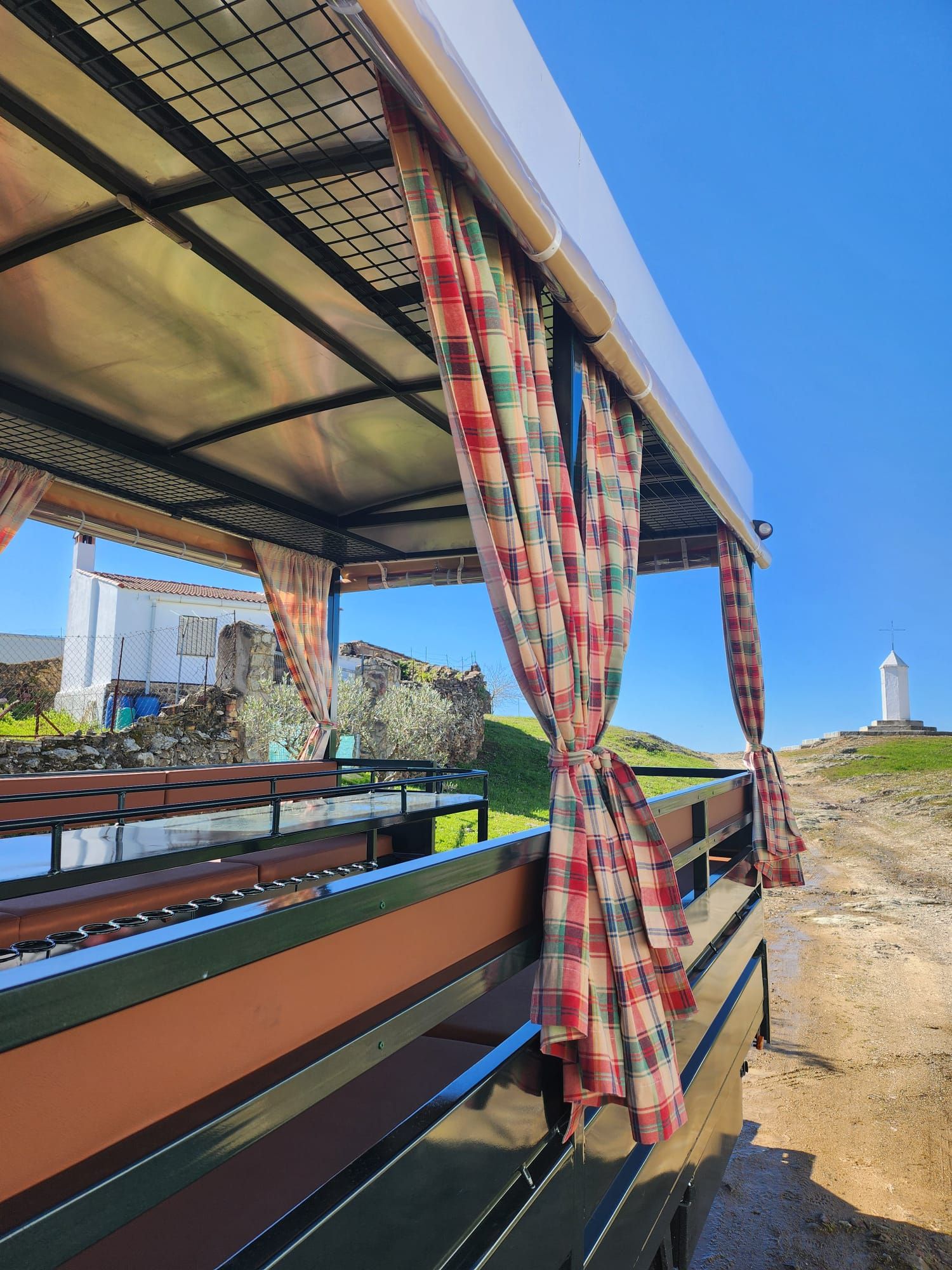 Asientos al aire libre cubiertos con cortinas a cuadros, con vistas a una escena costera con un faro.