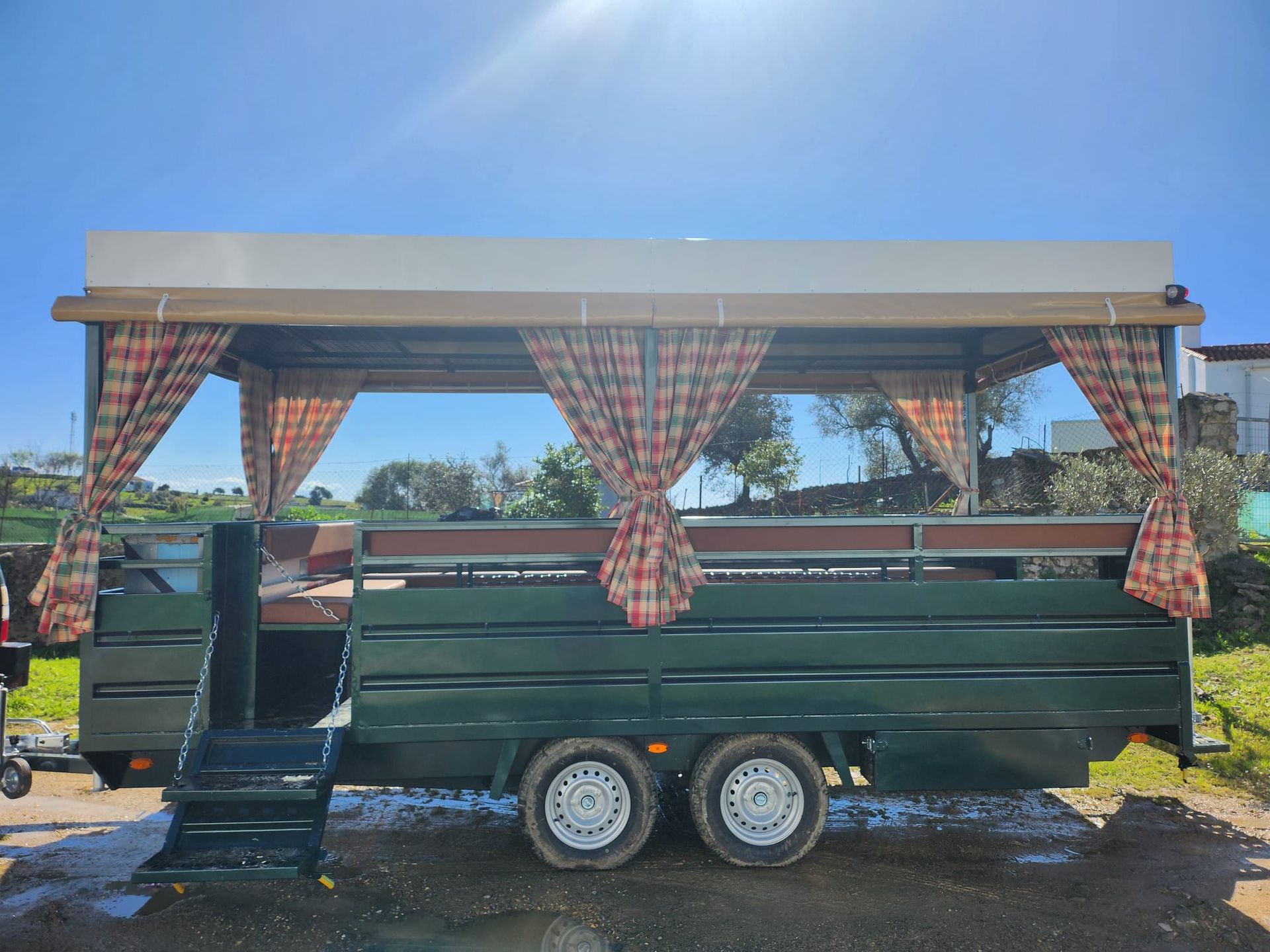 Remolque verde con cortinas, bajo un cielo soleado.