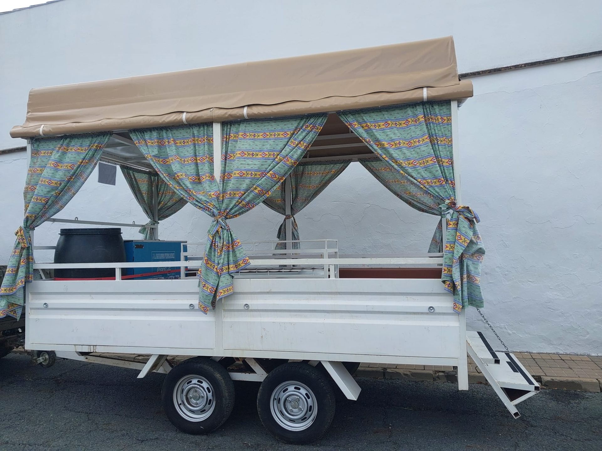 Remolque blanco con toldo color tostado y cortinas con estampado verde azulado.