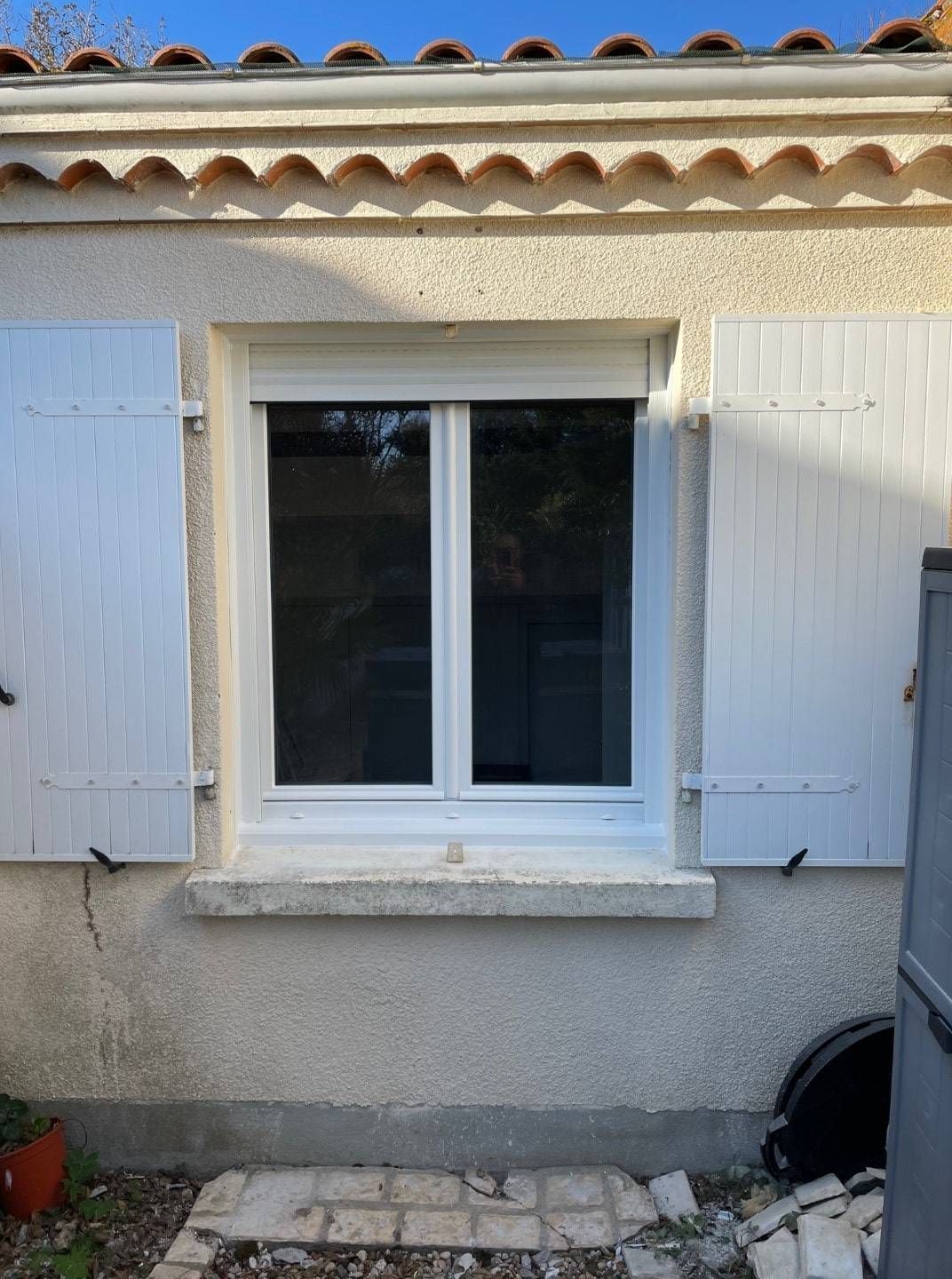 Fenêtre fermée avec volets battants blancs ouverts