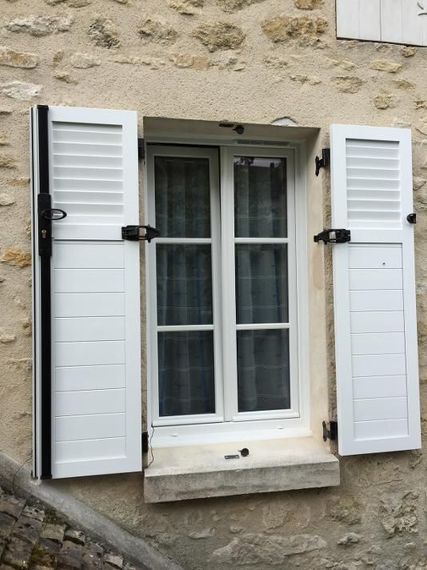 Extérieur d'une maison avec fenêtre et volets battants blancs