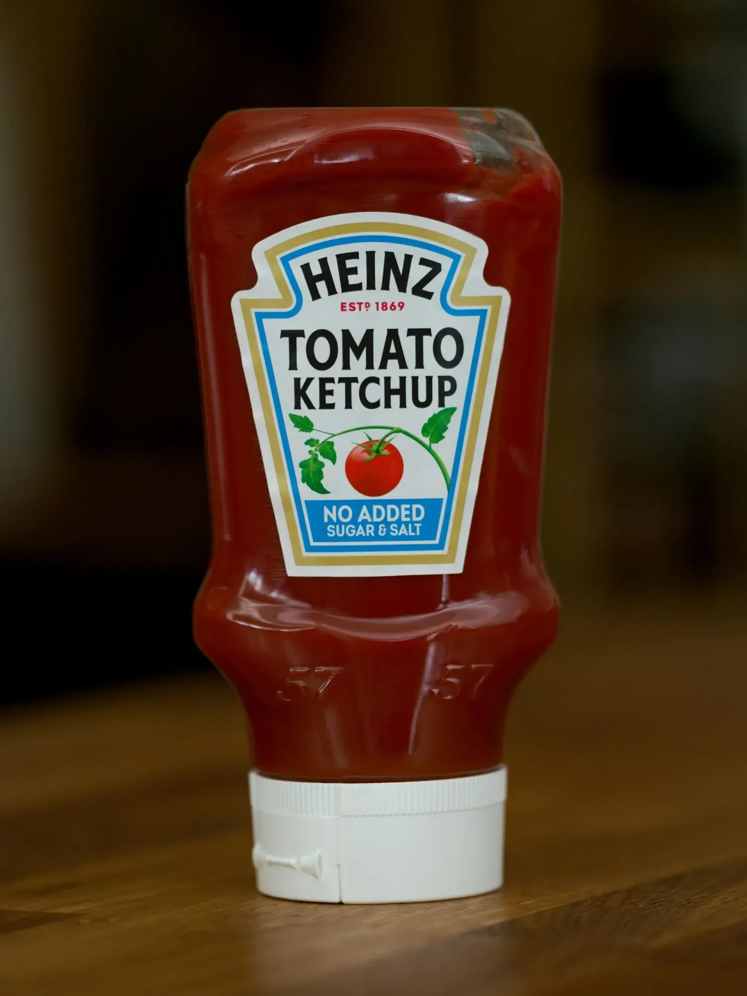 Botella de kétchup de tomate Heinz sobre una superficie de madera, mostrando la etiqueta y su contenido.