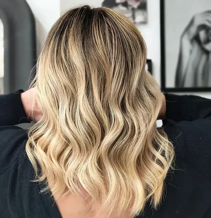 La parte posterior de la cabeza de una mujer con cabello rubio y una camisa negra.