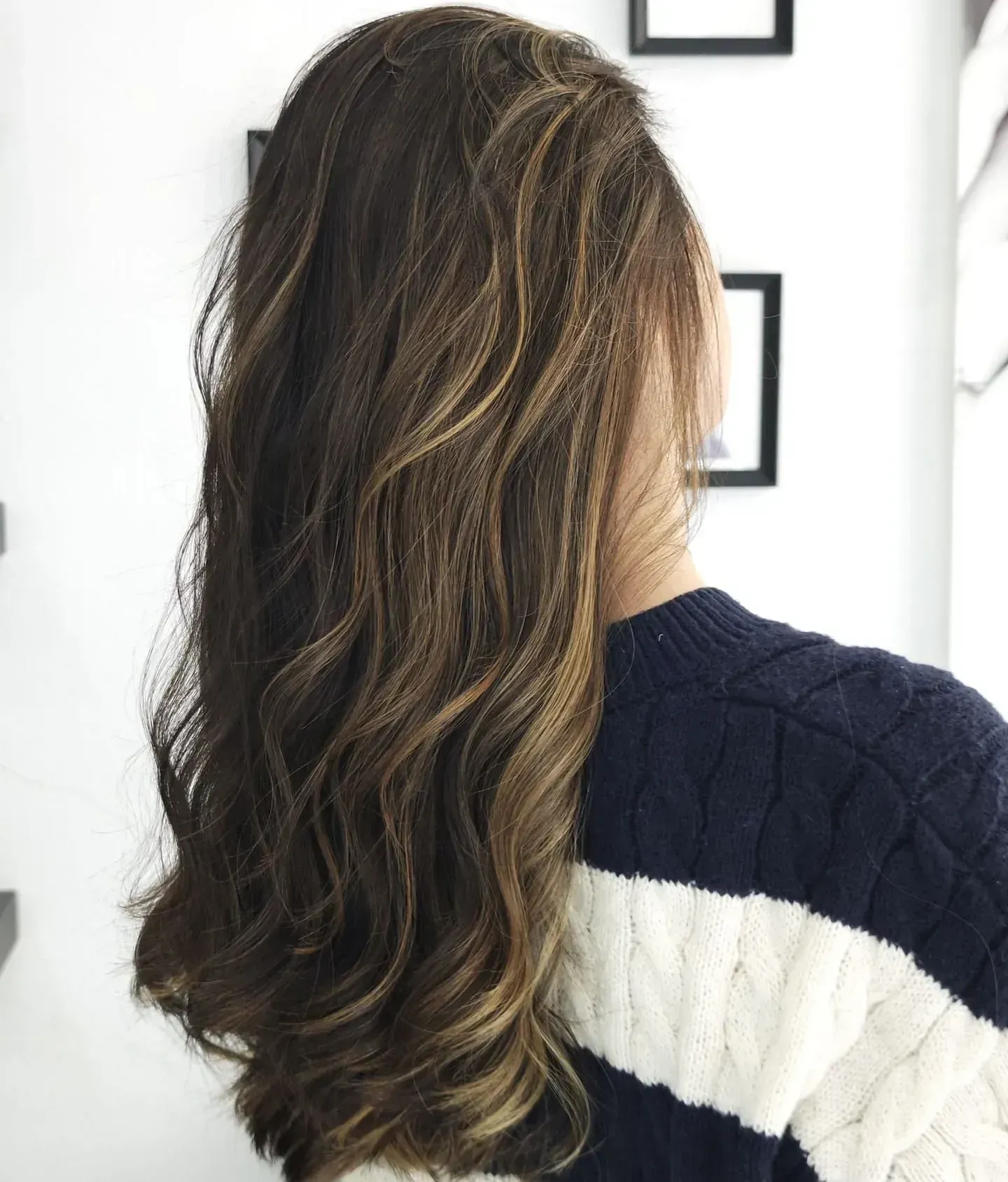 Una mujer con cabello largo lleva un suéter de rayas azules y blancas.