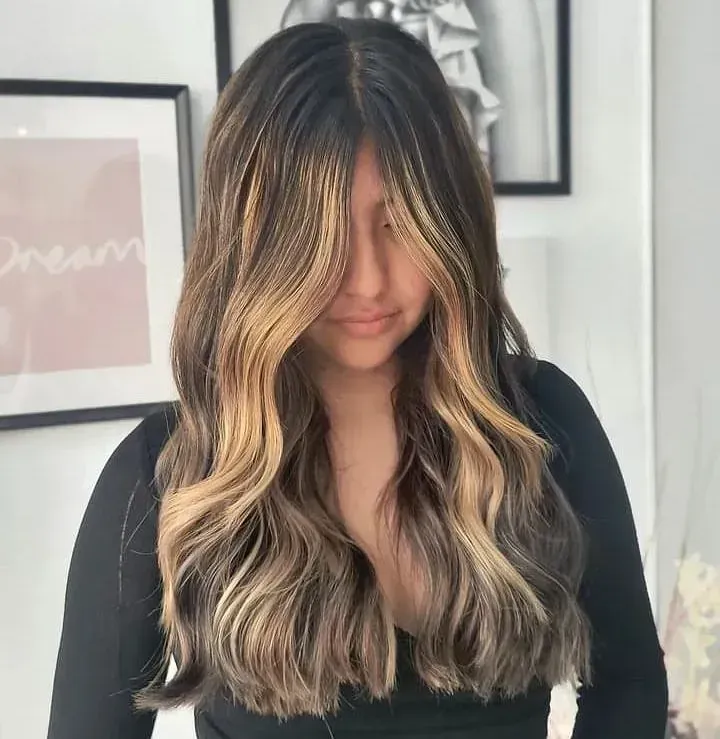 Una mujer con cabello largo y castaño lleva una camisa negra.