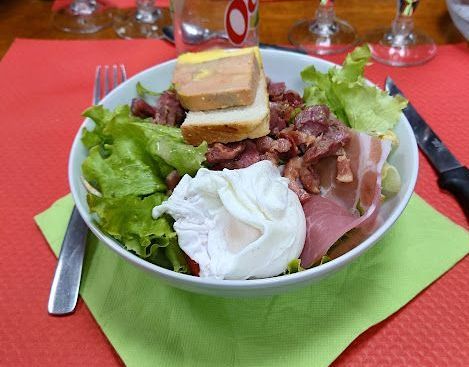 Une assiette avec la salade composée avec du jambon et œuf poché.