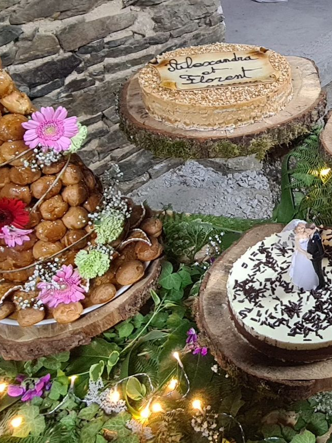 Gâteaux de mariage sur des plateaux en bois, décorés de fleurs et de verdure.