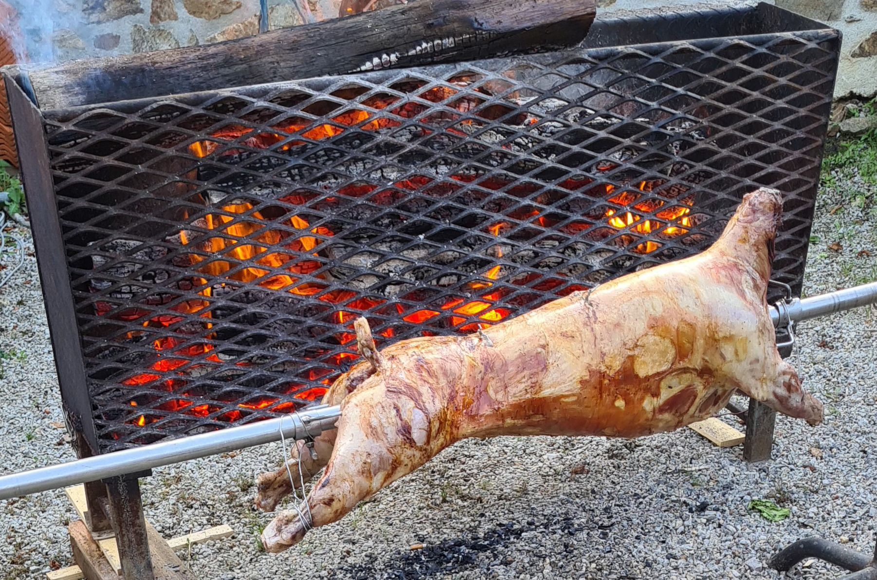 Un cochon rôti à la broche au-dessus d'un feu de charbon de bois.