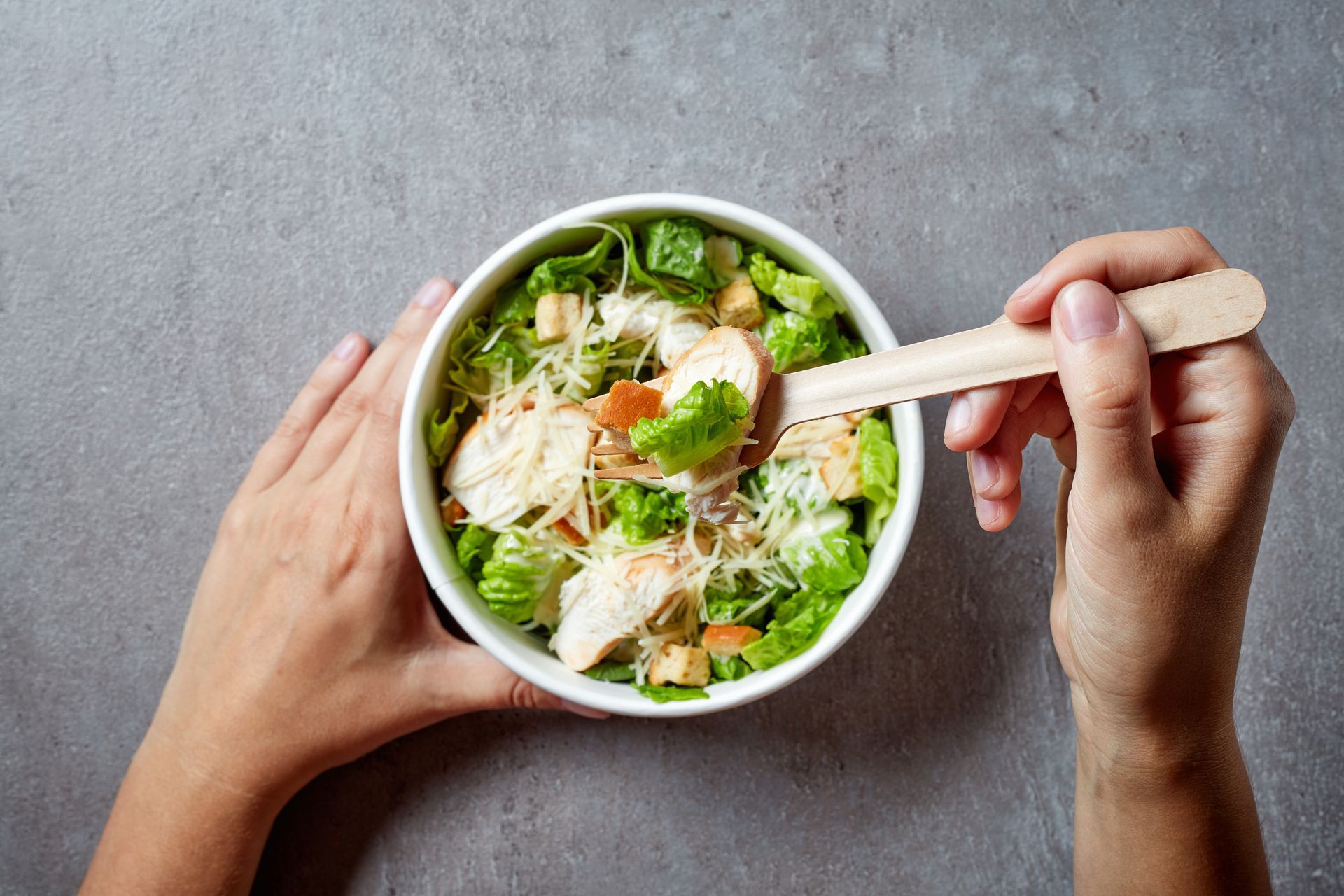 Une personne qui tient le bol avec la salade César.