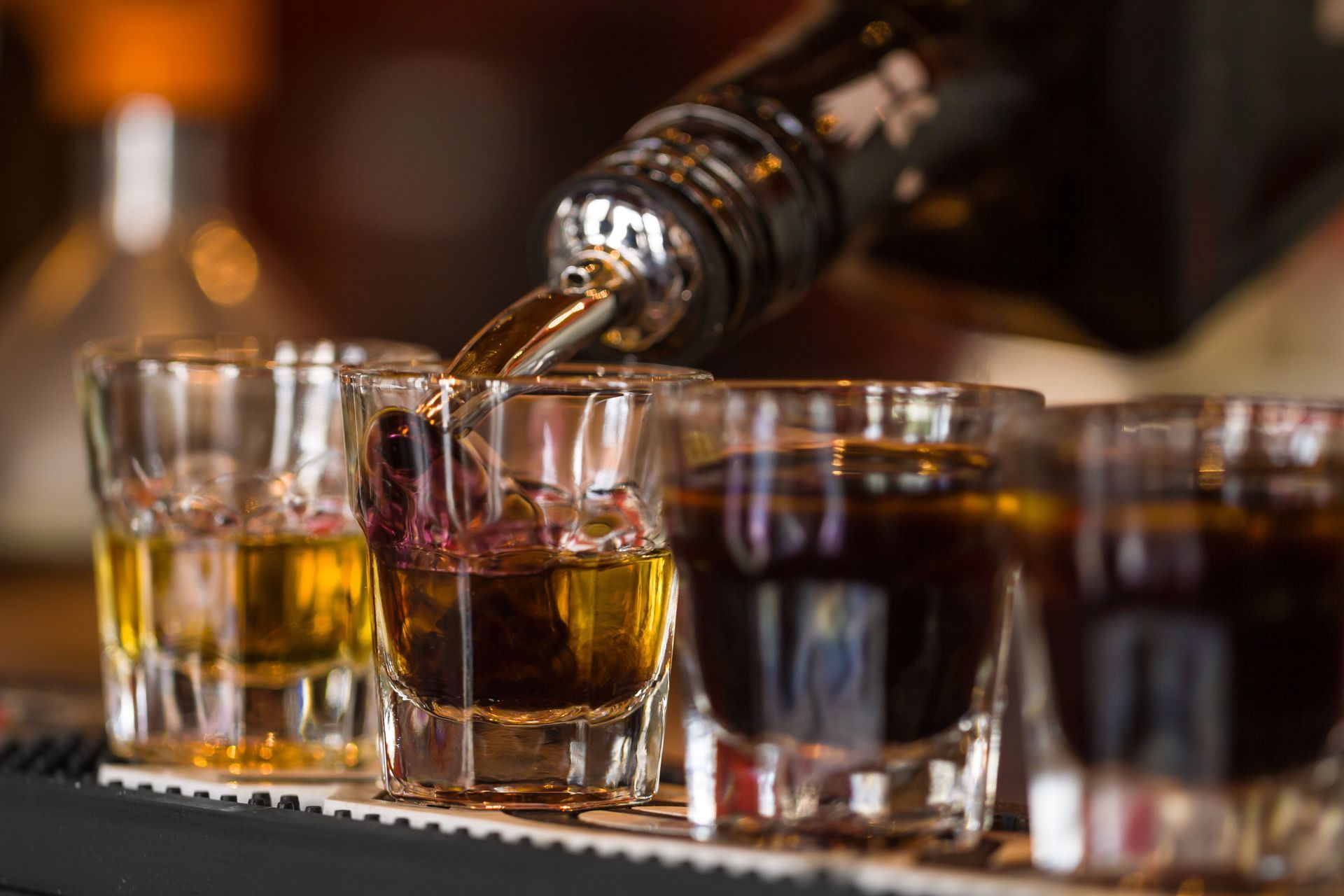 Plusieurs verres remplis du whisky posés sur le bar.