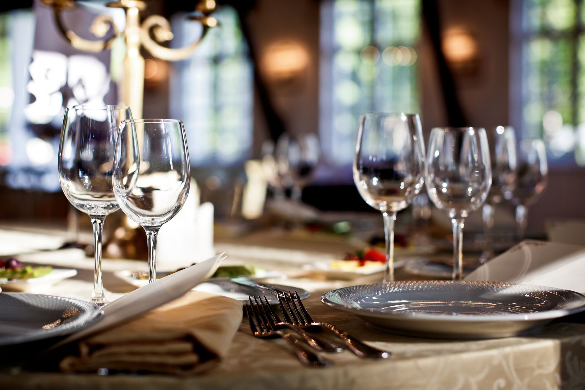 Une table dressée avec les verres, les assiettes et les fourchettes posées à côté.