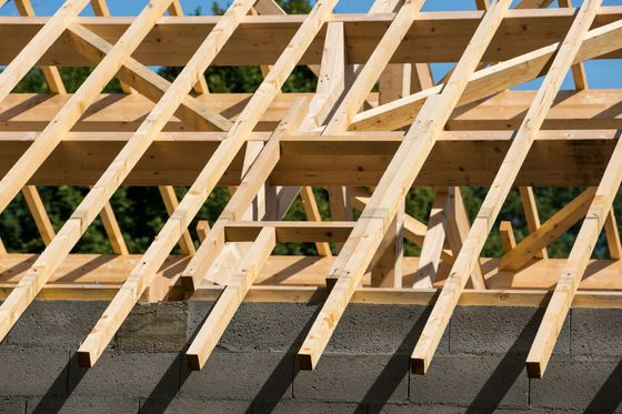Charpente de toit en bois en construction au-dessus d'un mur en parpaings.